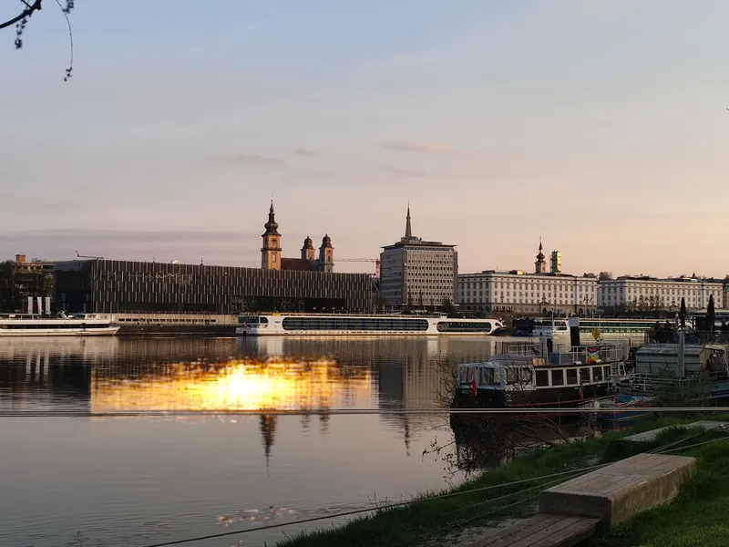 Linz bei Sonnenuntergang: Blick über die Donau auf das Lentos Kunstmuseum und die Türme der Altstadt